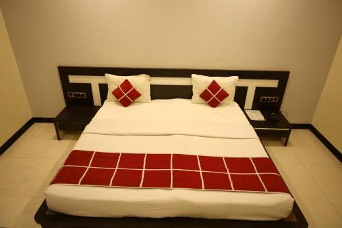 a bed with red and white sheets and pillows at Hotel Sparkling Pearl in Aurangabad