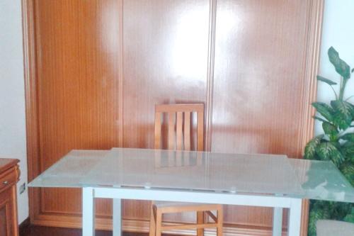 a glass table with two chairs and a wooden wall at Charming Apartment in El Grove, Sea View in O Grove