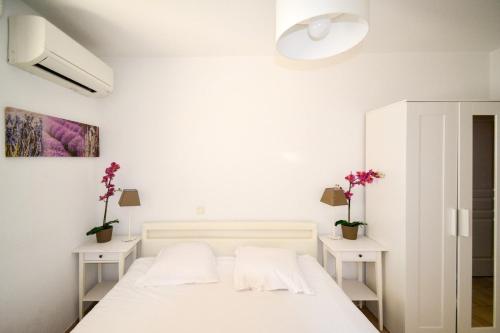 - une chambre avec un lit blanc et 2 tables blanches dans l'établissement Port Marianne avec terrasse et parking gratuit, à Montpellier
