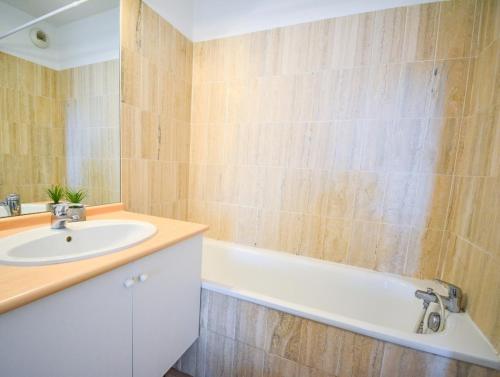 une salle de bain avec un lavabo et une baignoire dans l'établissement Port Marianne avec terrasse et parking gratuit, à Montpellier