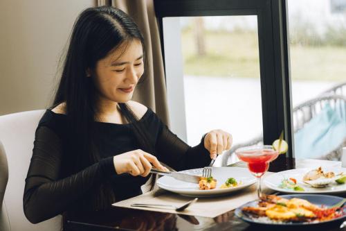 a woman sitting at a table with a plate of food at Seaside Boutique Resort Quy Nhon in Quy Nhon