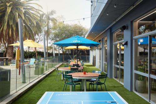 two tables and chairs with umbrellas on a patio at Together Co-Living Melbourne in Melbourne