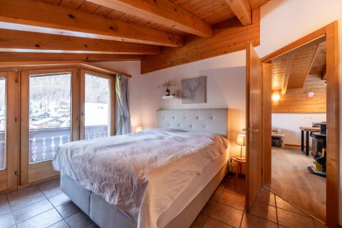 a bedroom with a bed in a room with a desk at Dachwohnung Balma-great overview of Zermatt in Zermatt