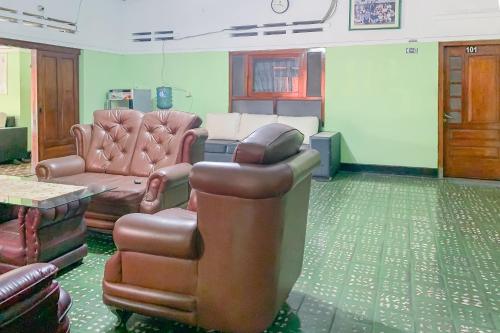a waiting room with a couch and a chair and a table at Urbanview Hotel Dasa Putra Syariah Sumedang in Parakankondang