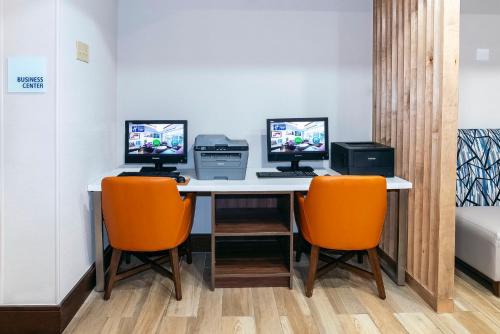 a desk with two monitors and two orange chairs at Holiday Inn Express & Suites Walterboro by IHG in Walterboro