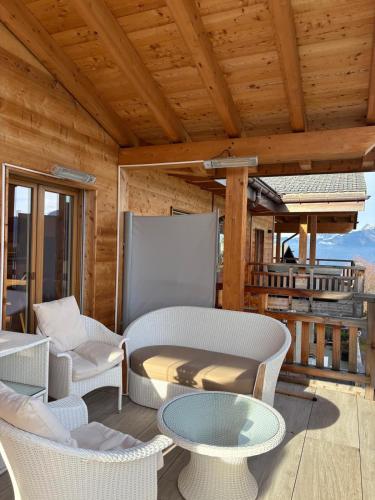 a patio with chairs and tables and a wooden ceiling at Loft de luxe en attique avec vues panoramiques in Vionnaz
