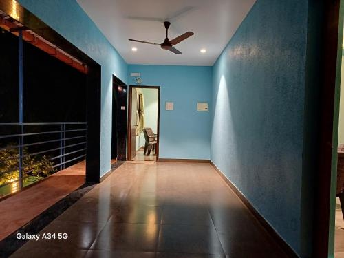 a hallway with blue walls and a ceiling fan at Nature's holiday home in Alibaug