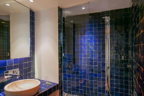 a bathroom with a toilet and a shower with blue tiles at Hôtel Le Bellechasse Saint-Germain in Paris