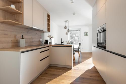 a kitchen with white cabinets and a wooden floor at Arton Lachtal - Apartments Steiermark in Lachtal