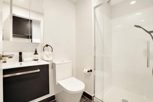 a white bathroom with a toilet and a shower at Stunning Studio Close to SkyTower - Pool Gym Sauna in Auckland