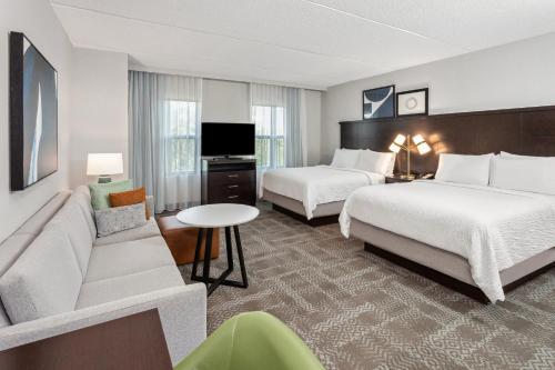 アルバニーにあるStaybridge Suites Albany Wolf Rd-Colonie Center by IHGのベッド2台とソファがあるホテルの部屋