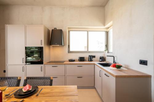 a kitchen with white cabinets and a wooden table at Lithos Art Villas in Sarlata
