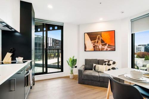 a kitchen and living room with a couch and a table at Cozy Aircon Studio Nearby Skytower - Pool Sauna Gym in Auckland