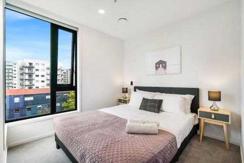 a bedroom with a bed and a large window at Cozy Aircon Studio Nearby Skytower - Pool Sauna Gym in Auckland