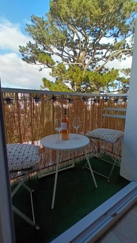 une table et des chaises sur un balcon avec un arbre dans l'établissement Appartement Cosy proche plage, à Carnac