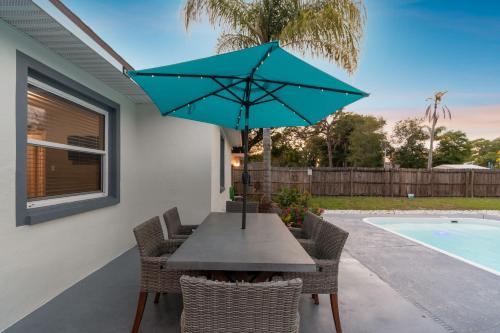 una mesa y sillas con una sombrilla azul en el patio en Tropical Retreat with Heated Pool & Firepit, en Clearwater