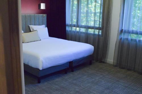 a bedroom with a white bed and a window at Best Western Plus Le Conquerant Rouen Nord in Bois-Guillaume