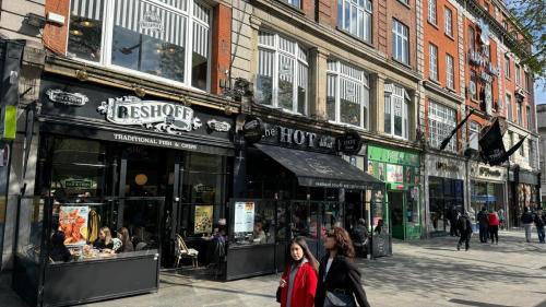 two women walking down a street in front of a store at Modern 2-Bedroom Apartment-Dublin City in Dublin