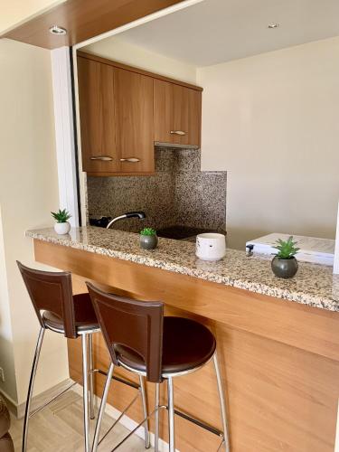 une cuisine avec un comptoir avec trois tabourets de bar dans l'établissement Gray d'Albion POL519 studio, à Cannes