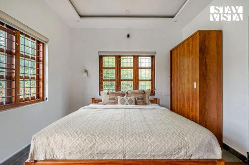 a bedroom with a large bed with a wooden cabinet at StayVista at Misty Village - BBQ, Bonfire & Meals in Pooppara