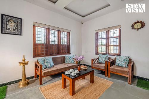 a living room with two couches and a table at StayVista at Misty Village - BBQ, Bonfire & Meals in Pooppara