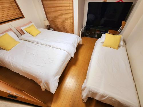 two beds with yellow pillows in a room at Takaraboshi room 201 Sannomiya 10 min in Kobe