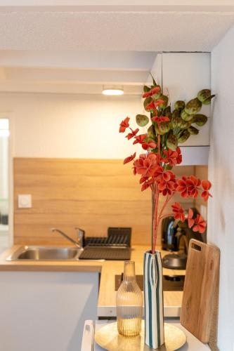 un vase avec des fleurs rouges sur un comptoir de cuisine dans l'établissement Le Péri - Douillet appartement en Hypercentre, à Toulouse