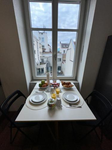 une table avec des assiettes de nourriture et une fenêtre dans l'établissement # Le 3 # Joli appartement T3 Mulhouse centre, Neuf, calme et tout équipé, à Mulhouse