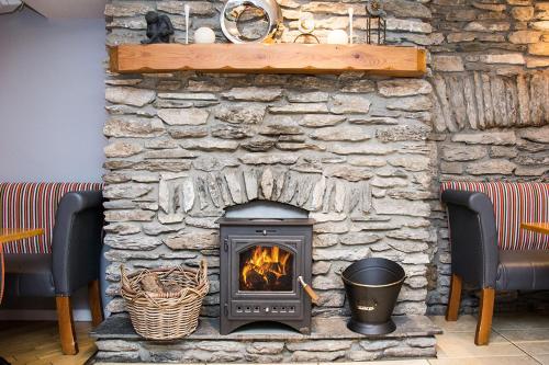 a stone fireplace with a stove in a room at Davitts Guesthouse in Kenmare