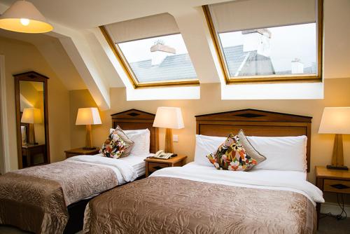 a hotel room with two beds and two windows at Davitts Guesthouse in Kenmare