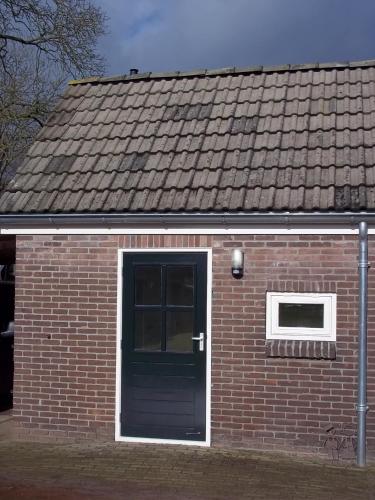 a brick building with a green door and a window at B&B Slaoperij in Orvelte