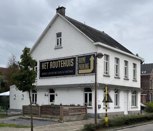 a white building with a sign on the side of it at B&B Het Routehuis in Hulshout