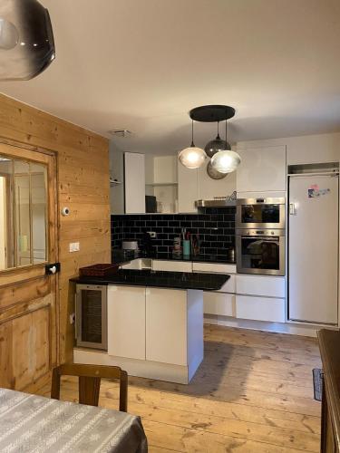 une cuisine avec des armoires blanches et un réfrigérateur blanc dans l'établissement Maison Boule de Neige, meublé de tourisme 3 étoiles, à Formiguères