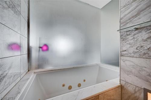 a white bath tub in a bathroom with pink bubbles at Beautiful Mountain View Palms Studio 30307 in Las Vegas