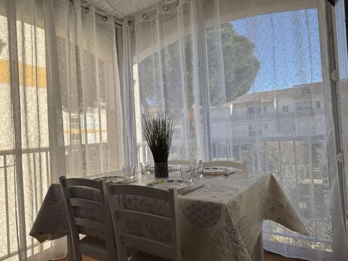 une table blanche et des chaises dans une pièce avec une fenêtre dans l'établissement Appartement 2 pièces cabine 4 couchages ARGELES SUR MER AR020-207, à Argelès-sur-Mer