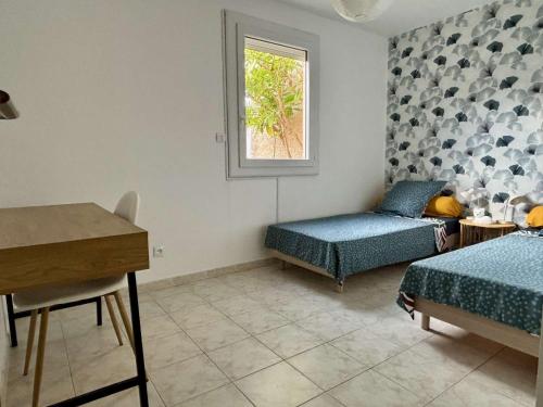 une chambre avec deux lits et un bureau et une fenêtre dans l'établissement Maison 3 pièces avec jardin et terrasse - Jusqu'à 4 personnes - ARGELES SUR MER AR000-014, à Argelès-sur-Mer