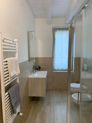 a bathroom with a sink and a toilet and a window at Appartamento GARDA in Padenghe sul Garda