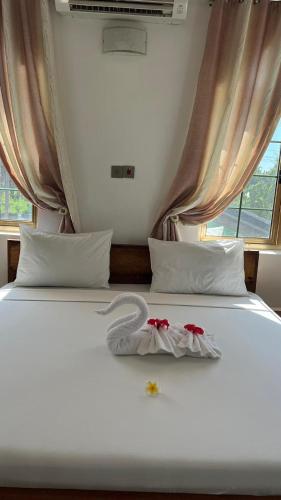 a white bed with two red flowers on it at skyport villa in Zanzibar City