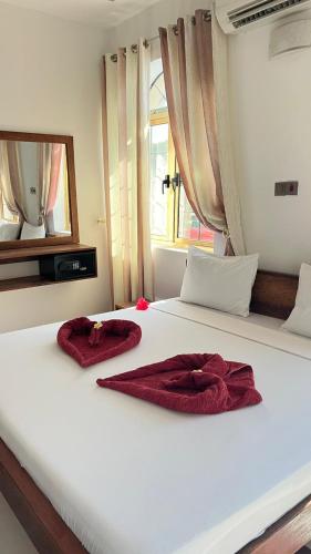 a white bed with two red towels on it at skyport villa in Zanzibar City