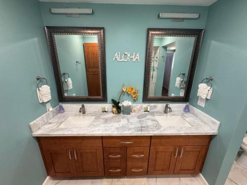 a bathroom with two sinks and two mirrors at Casa De Emdeko 230 in Kailua-Kona