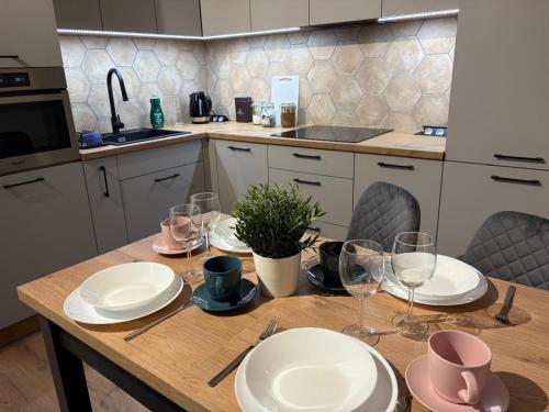 a kitchen with a wooden table with plates and wine glasses at Tabago Studio 26 Zduńska Wola Gierymskiego in Zduńska Wola