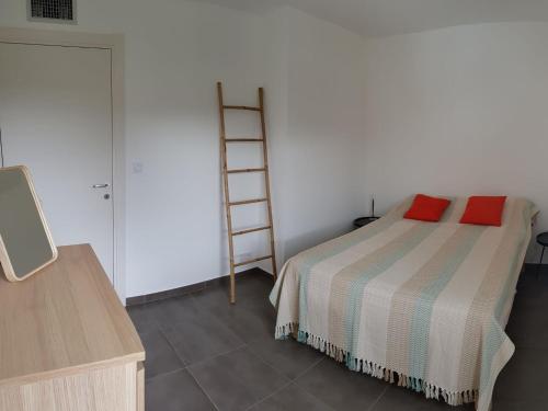 une chambre avec un lit avec deux oreillers rouges dessus dans l'établissement PORTICCIO Appart 6pers Climatisé proche plage, à Porticcio