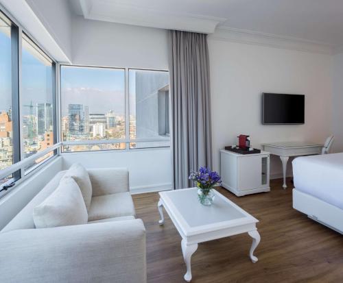 a living room with a white couch and a large window at NH Collection Plaza Santiago in Santiago