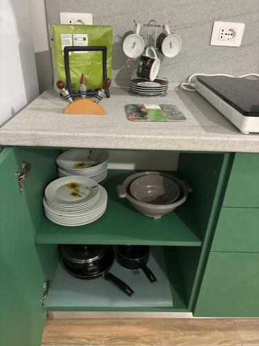 a green cabinet with plates and dishes in it at Come a Casa in Vittuone
