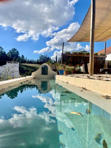 a swimming pool with a blue sky and clouds at Casa Amador in Alcácer do Sal