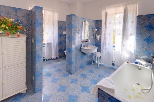 a blue tiled bathroom with a sink and a tub at Affittacamere Villa Gigli in Sirolo