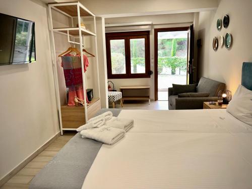 a bedroom with a large white bed and a living room at PORTO PORTES suites in Nea Potidaea