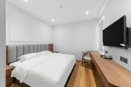 ムアルにあるMilux Hotelの白いベッドと薄型テレビのある寝室