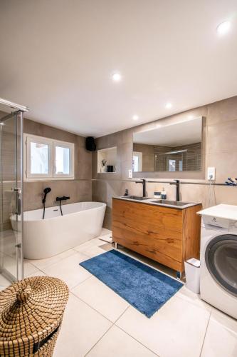 La salle de bains est pourvue d'une baignoire, d'un lavabo et d'un lave-linge. dans l'établissement Maison 4 chambres avec jaccuzi piscine privée et sauna, à Apremont