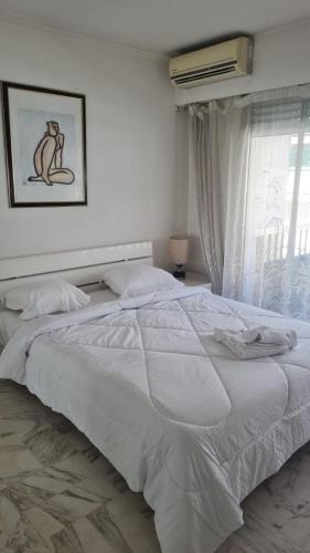 un grand lit blanc dans une chambre avec une fenêtre dans l'établissement 2 Bedroom Martinez Side, à Cannes